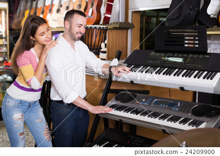 Saleswoman helping man to select synthesisers 24209900