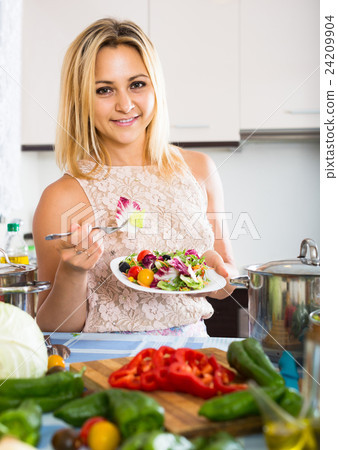 girl standing at kitchen table with plate of salad girl standing at kitchen table with plate of salad 24209904