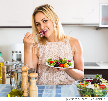 girl standing at kitchen table with plate of salad girl standing at kitchen table with plate of salad 24209934