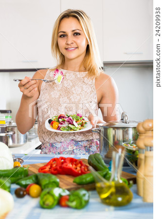 girl standing at kitchen table with plate of salad girl standing at kitchen table with plate of salad 24209938