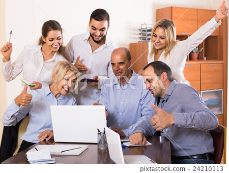 colleagues looking at laptop and smiling colleagues looking at laptop and smiling 24210113