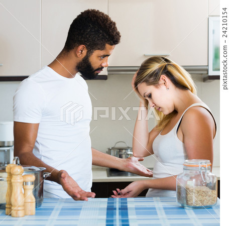 interracial family couple with serious faces quarrelling in kitchen 24210154