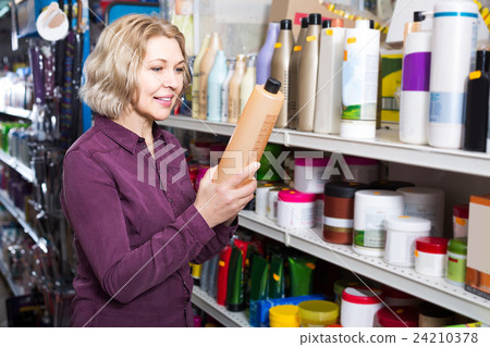 mature female customer buying volume shampoo in supermarket hair section mature female customer buying volume shampoo in supermarket hair section 24210378