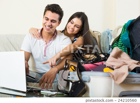 adults sitting near laptop and luggage 24210560