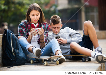 Friends relaxing with mobile phones Friends relaxing with mobile phones 24210782