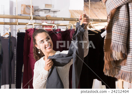 Adult female brunette choosing trousers in shop Adult female brunette choosing trousers in shop 24212404
