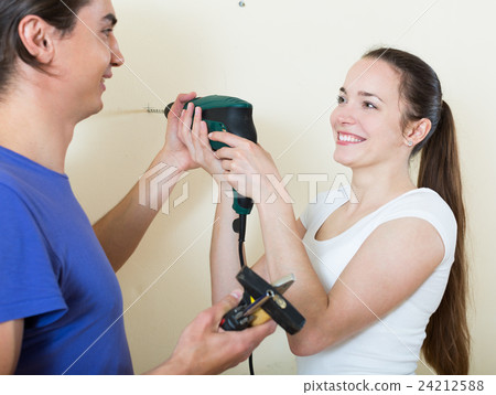 couple drilling wall with drill at home 24212588
