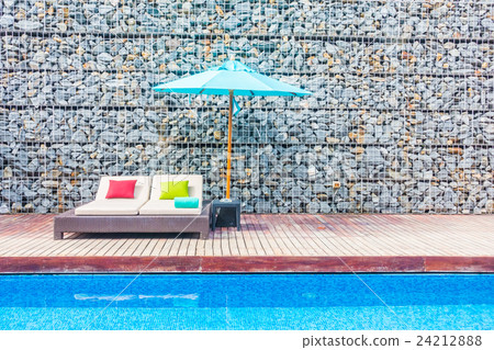 Umbrella and chair around swimming pool 24212888