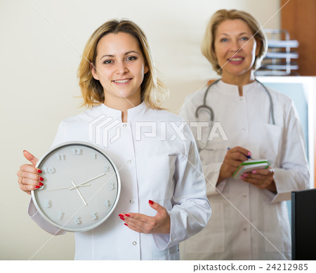 Two female doctors showing time in clock 24212985