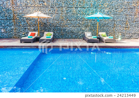 Umbrella and chair around swimming pool 24213449