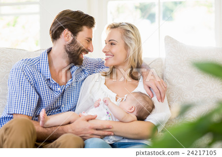 Parents sitting on sofa with their child 24217105