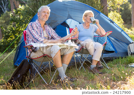 Senior couple relaxing beside their tent Senior couple relaxing beside their tent 24217900