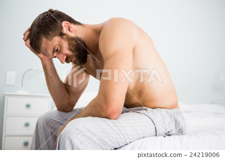 Depressed man on bed with hand on head 24219006