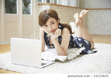 A woman lying down and operating a PC 24229820
