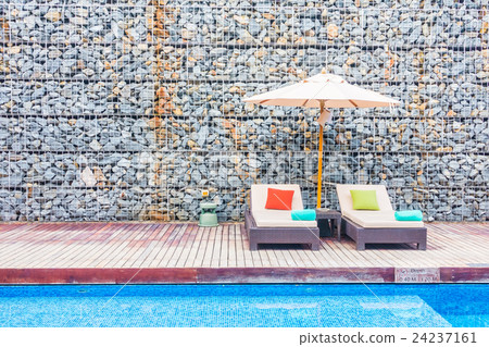 Umbrella and chair around swimming pool 24237161