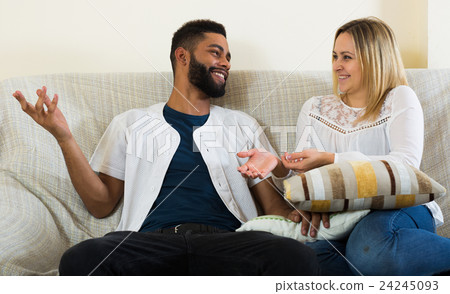 Young interracial couple chatting and laughing indoors Young interracial couple chatting and laughing indoors 24245093