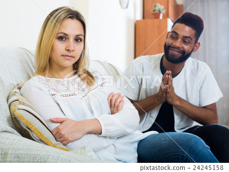 Indoors portrait of mixed couple trying to reconcile after quarrel 24245158