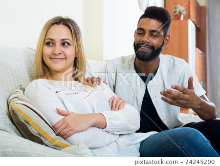 Indoors portrait of mixed couple trying to reconcile after quarrel 24245200
