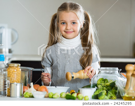 Smiling little girl learning to cook in kitchen Smiling little girl learning to cook in kitchen 24245295