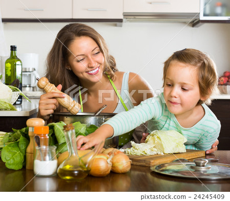 Mother with little daughter cooking at home 24245409