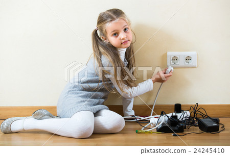 Little girl playing with sockets at home. 24245410