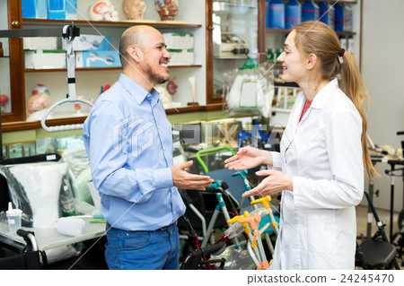 Female consultant offering wheelchair to mature customer 24245470