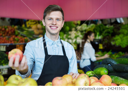 Young male dealer lays out the apples 24245501