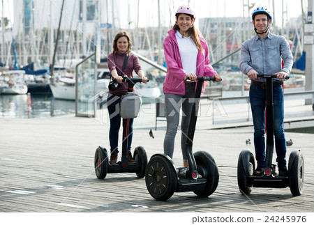 Girls and guy traveling through city by segways Girls and guy traveling through city by segways 24245976