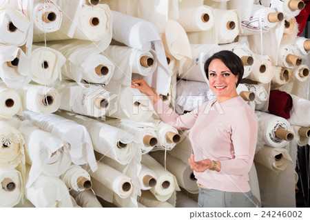 Portrait of happy mature woman with cloth rolls 24246002