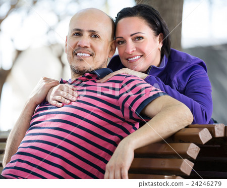 Couple sitting together on bench 24246279