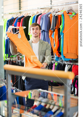 Young man choosing a t-shirt in the store. Young man choosing a t-shirt in the store. 24246365