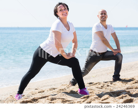man and woman exercising together on the beach 24246369