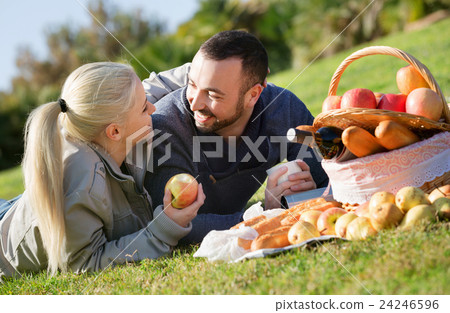 Loving young beautiful couple chatting as having picnic Loving young beautiful couple chatting as having picnic 24246596