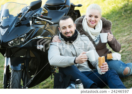 Couple drinking coffee near motorcycle 24246597