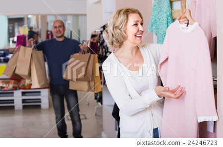 wife buying dress at apparel store, man is bored wife buying dress at apparel store, man is bored 24246723