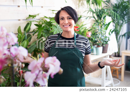 Glad woman florist smiling among the potted plants Glad woman florist smiling among the potted plants 24247105