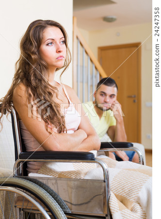 Sad man with girlfriend in invalid chair Sad man with girlfriend in invalid chair 24247358