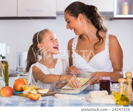 Housewife with daughter cooking apple pie. Housewife with daughter cooking apple pie. 24247359