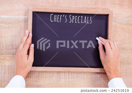 Composite image of chef hand writing on a chalkboard 24251619