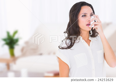Composite image of asthmatic brunette using her inhaler  24251629