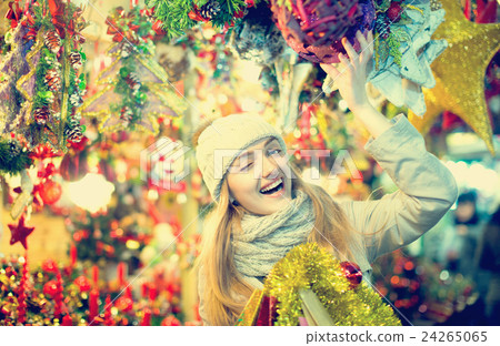 Smiling young woman choosing Christmas decoration at market 24265065
