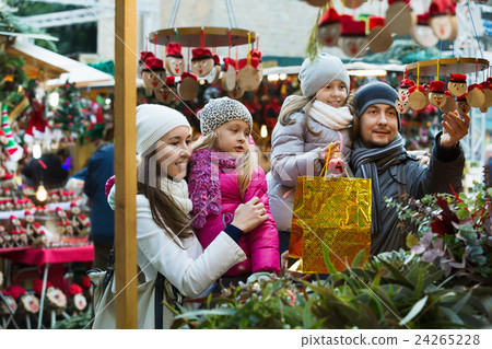 Happy cheerful family of four buying Caga Tio. Focus on woman and ittle girl Happy cheerful family of four buying Caga Tio. Focus on woman and ittle girl 24265228