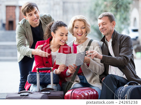 Family of four with luggage checking direction in map 24265238