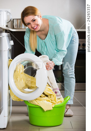 Portrait of housewife with bed linen near washer Portrait of housewife with bed linen near washer 24265357