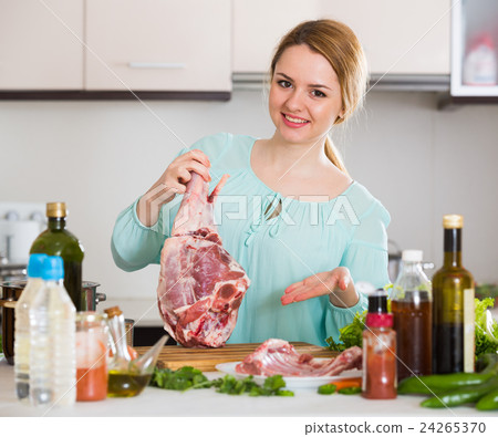 Girl preparing mutton in kitchen and smiling Girl preparing mutton in kitchen and smiling 24265370