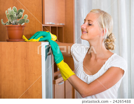 Blonde girl dusting in living room 24265488