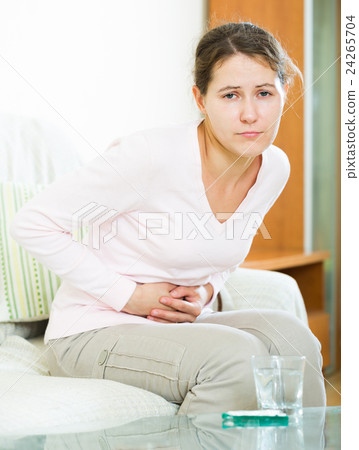 Portrait of girl folding up with belly pain indoor Portrait of girl folding up with belly pain indoor 24265704
