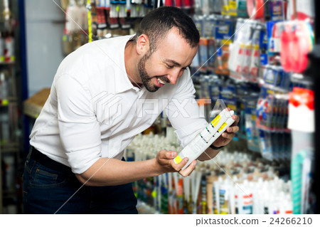 Man choosing sealant tube 24266210
