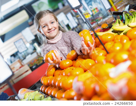 Cheerful smiling little girl purchasing sweet mandarines 24266650