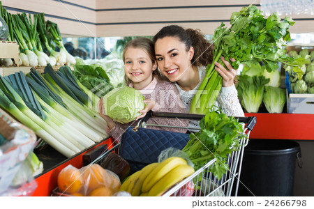 Mother with smiling small daughter buying celery and cabbage Mother with smiling small daughter buying celery and cabbage 24266798